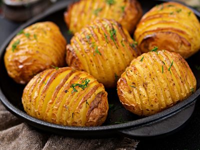 Baked potato with herbs on black background. Vegan food. Healthy meal.